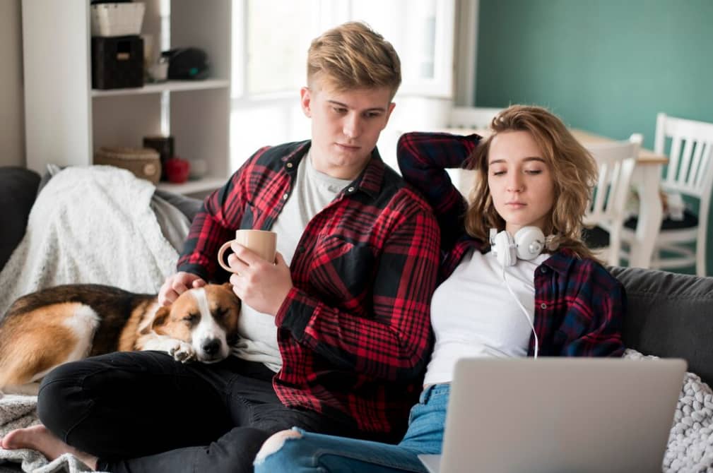 A couple with a dog relaxing on a couch