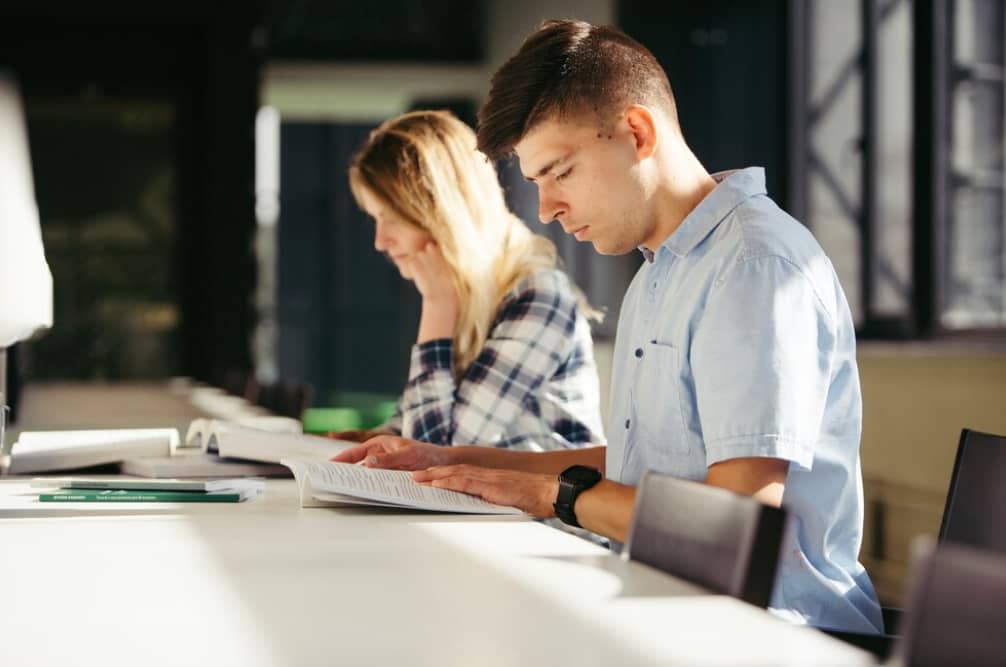A young man and woman focused on reading at a table